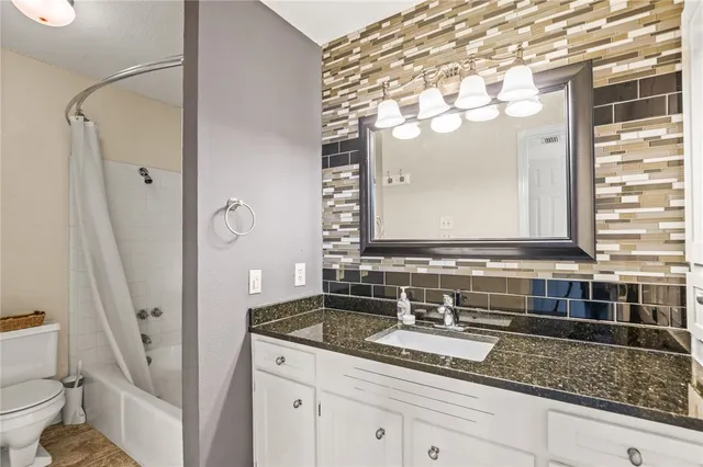 a bathroom with a granite countertop sink a mirror a vanity and a shower