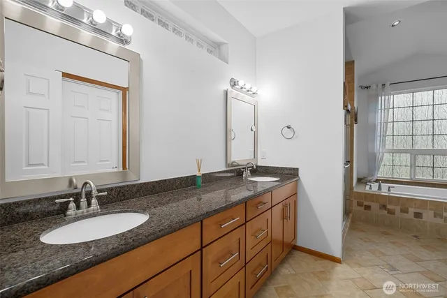a bathroom with a granite countertop double vanity sink and a mirror