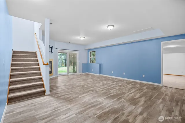 a view of an empty room with wooden floor and stairs