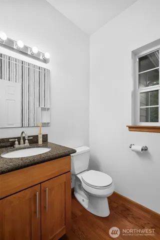 a bathroom with a granite countertop toilet sink and mirror