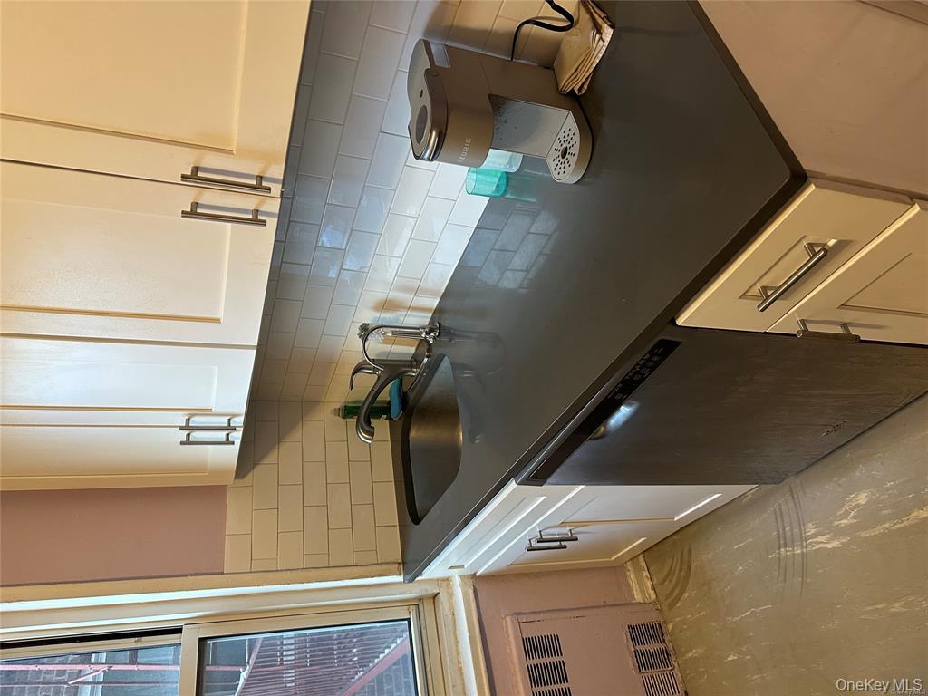 34-10 75th Street, Unit 3L Queens, NY 11372 - Photo 6 of 18 Kitchen with dishwasher, a sink, radiator, dark countertops, and white cabinets