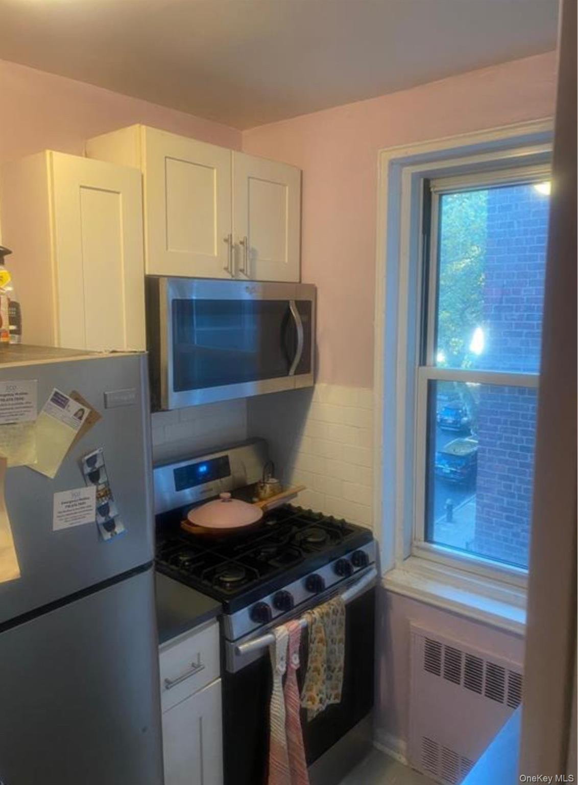 34-10 75th Street, Unit 3L Queens, NY 11372 - Photo 7 of 18 Kitchen featuring appliances with stainless steel finishes, radiator, and white cabinets