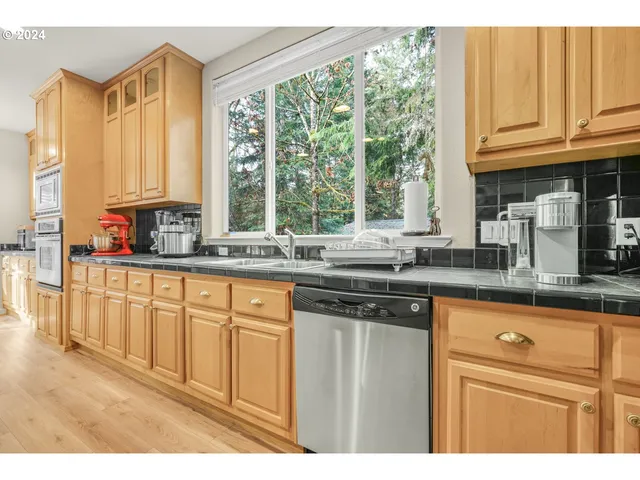 a kitchen with stainless steel appliances granite countertop a sink a stove and cabinets