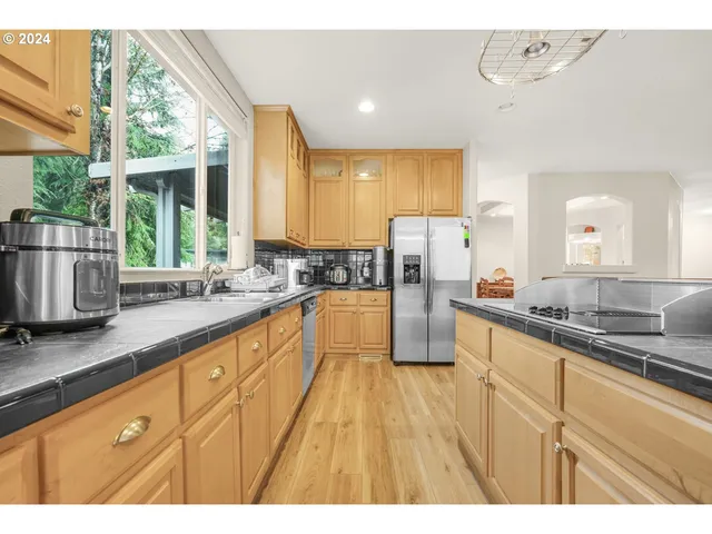 a large kitchen with granite countertop a sink window and cabinets