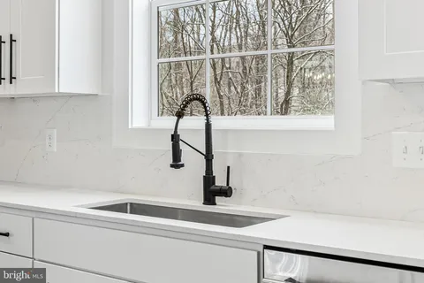 a kitchen with stainless steel appliances granite countertop a stove a sink and white cabinets