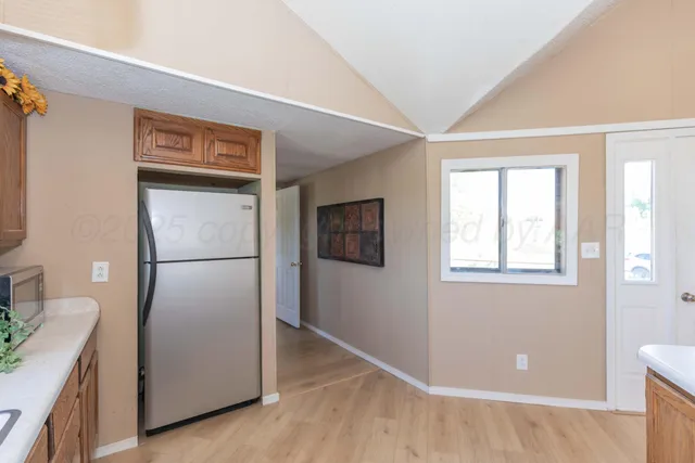 a view of a kitchen with a fridge and wooden floor