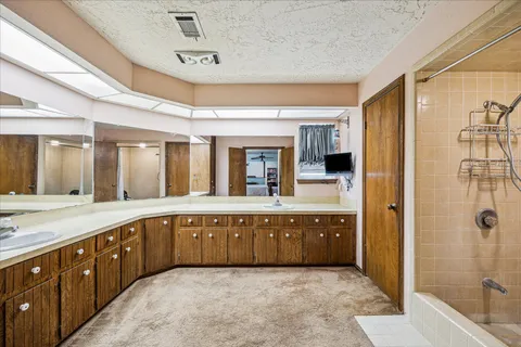 a large bathroom with a granite countertop tub sink shower and mirror