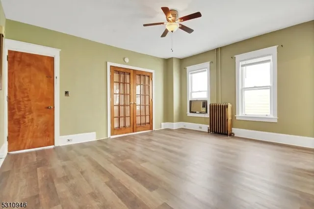 a view of an empty room with a window and wooden floor