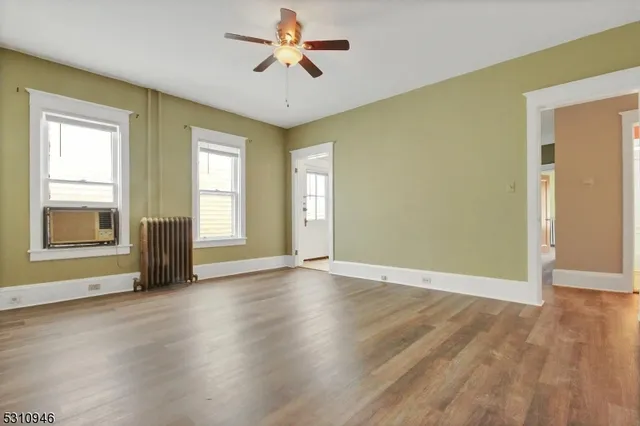 a view of an empty room with a window and wooden floor