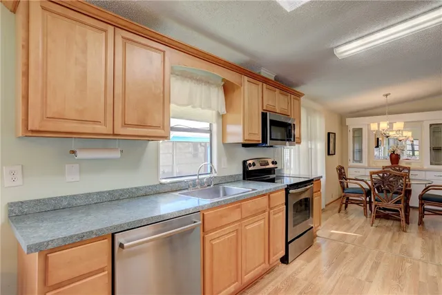 a kitchen with stainless steel appliances granite countertop a stove top oven a sink dishwasher a dining table and chairs with wooden floor