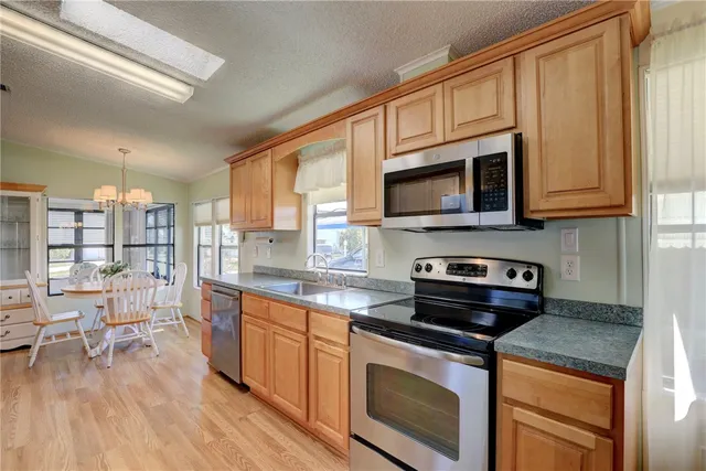 a kitchen with stainless steel appliances granite countertop a stove a sink dishwasher and a microwave oven with wooden floor