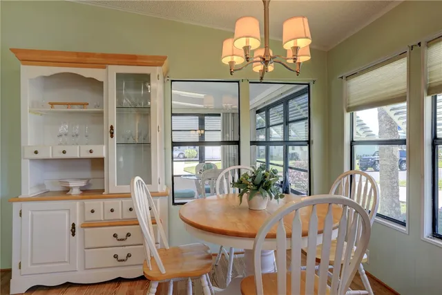 a dining room with wooden floor a chandelier a wooden table and chairs