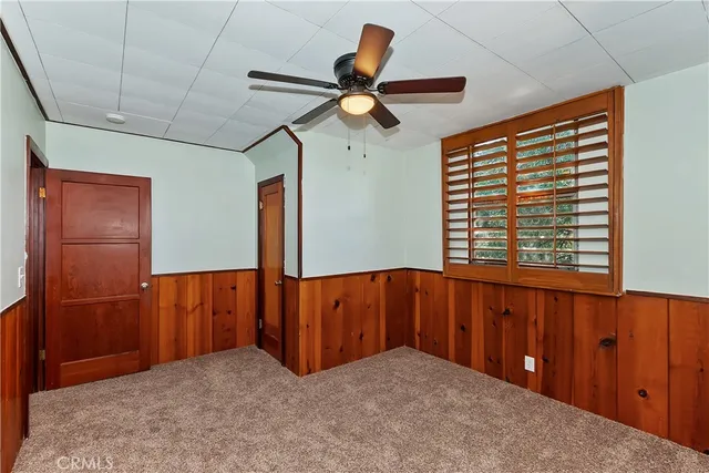 a room with a dresser and a ceiling fan