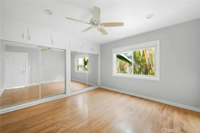 an empty room with wooden floor mirror and windows