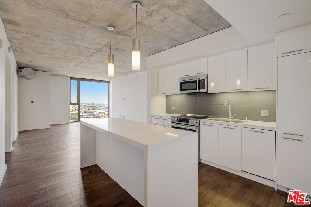 8500 West Sunset, Unit E711 Los Angeles, CA 90069 - Photo 7 of 10 a kitchen with stainless steel appliances granite countertop a stove a refrigerator a sink and a microwave