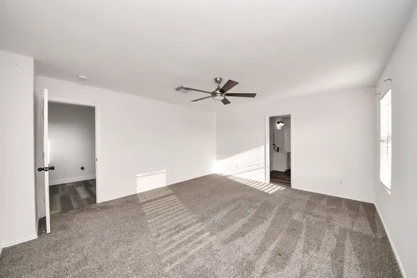 an empty room with a window and a fan