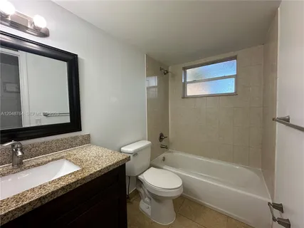 a bathroom with a granite countertop sink mirror vanity and toilet