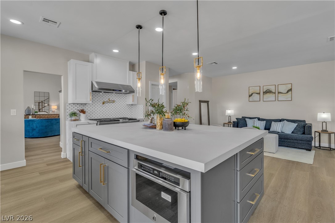 8848 Rainbow Ridge Drive Las Vegas, NV 89117 - Photo 9 of 43 An open concept kitchen features an island with seating, pendant lighting, and flows seamlessly into the living space.