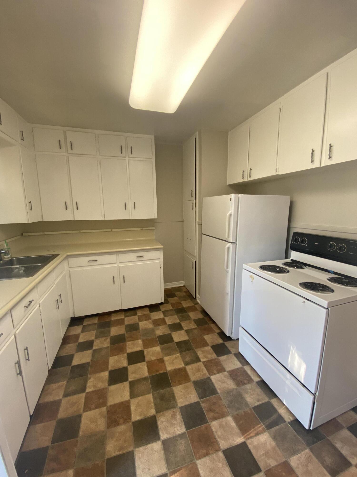 4603 45th Street Lubbock, TX 79414 - Photo 3 of 7 a kitchen with a checkered floor and white cabinets