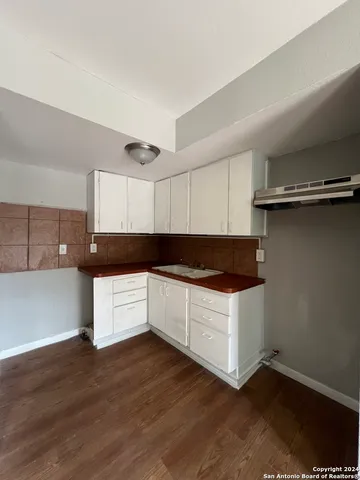 a kitchen with granite countertop a white cabinets and wooden floor