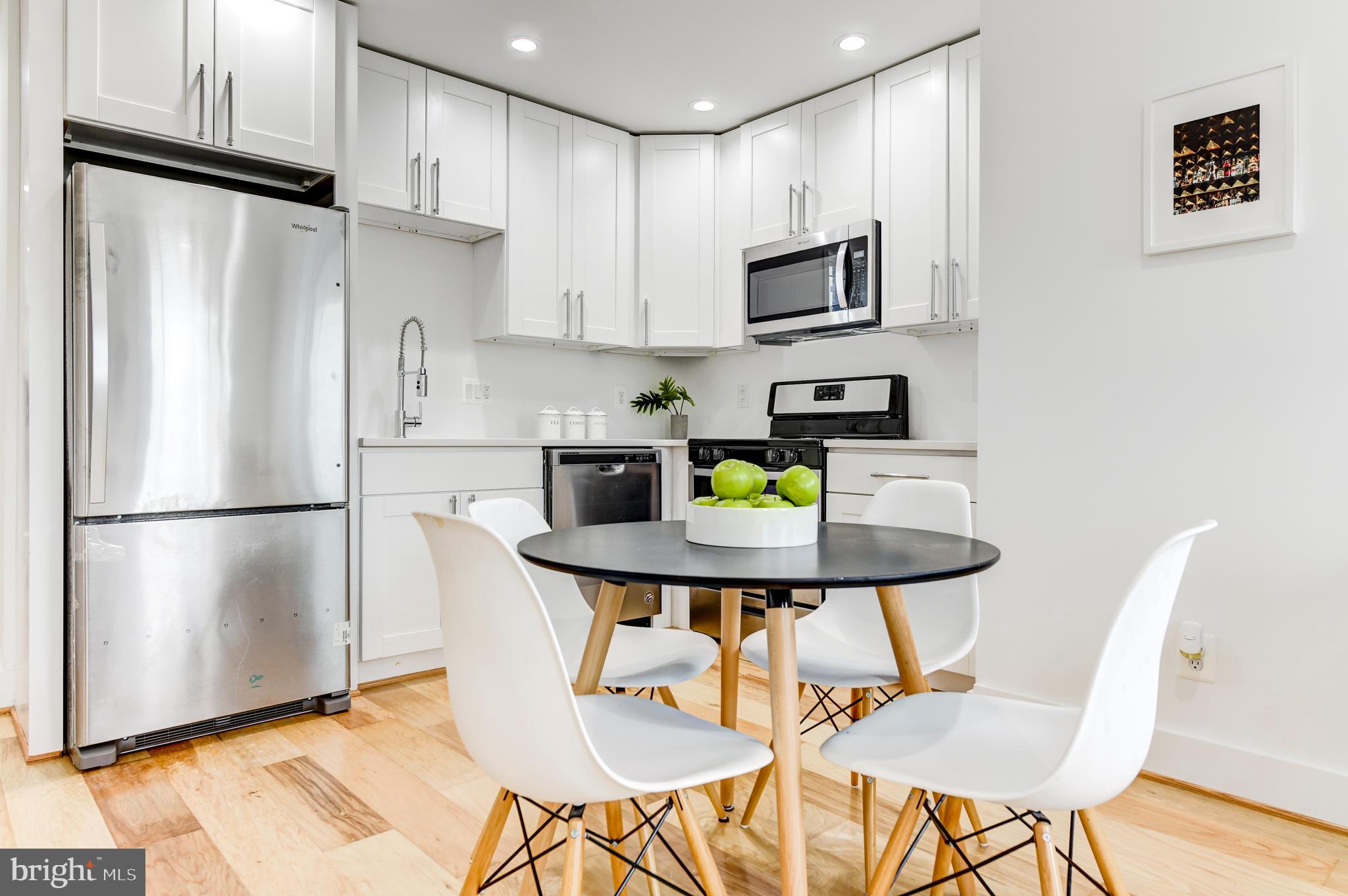 408 Newcomb Street Southeast Washington, DC 20032 - Photo 4 of 8 a white kitchen with stainless steel appliances a refrigerator a stove a sink dishwasher and white cabinets with wooden floor