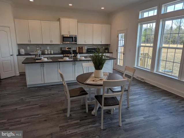 a kitchen with granite countertop a table chairs stove and cabinets