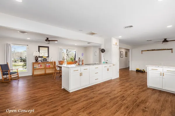 a large white kitchen with wooden floors and a fireplace