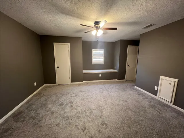 a view of an empty room with a ceiling fan and window