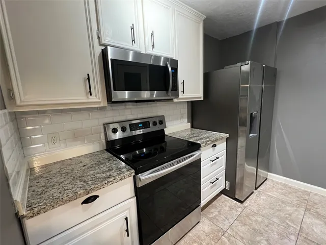 a kitchen with stainless steel appliances granite countertop a stove microwave and refrigerator
