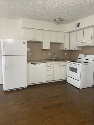 a kitchen with stainless steel appliances granite countertop a stove a sink and white cabinets