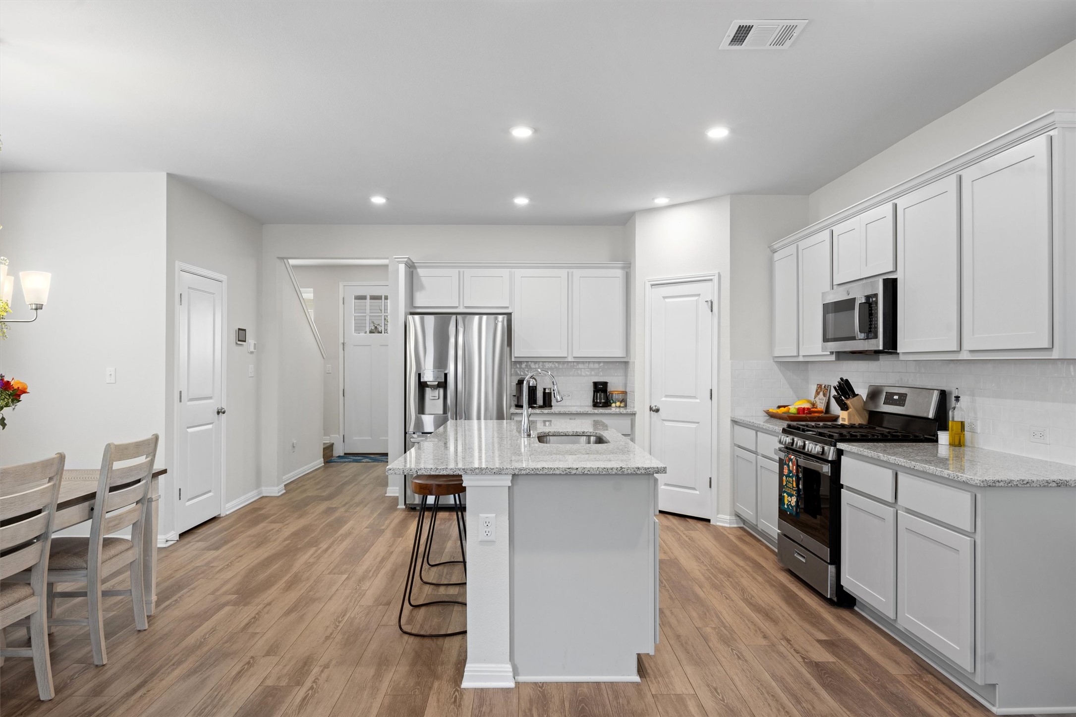 313 Toddy Way Leander, TX 78641 - Photo 12 of 39 Kitchen with appliances with stainless steel finishes, backsplash, light stone countertops, light wood finished floors, and recessed lighting