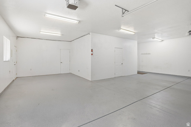 2190 750 West Perry, UT 84302 - Photo 35 of 42 Spacious garage featuring a light gray epoxy floor coating, multiple fluorescent lighting fixtures, and direct access doors