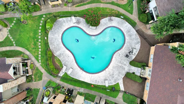 an aerial view of a swimming pool with outdoor seating and yard