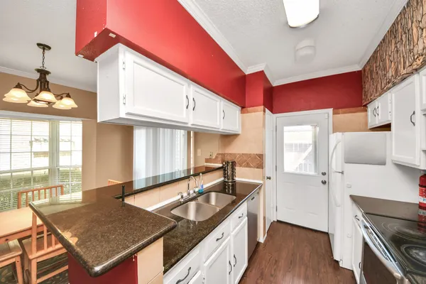 a kitchen with granite countertop a stove a sink and a refrigerator