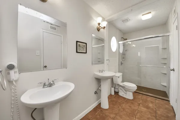 a bathroom with a sink a toilet a mirror and shower
