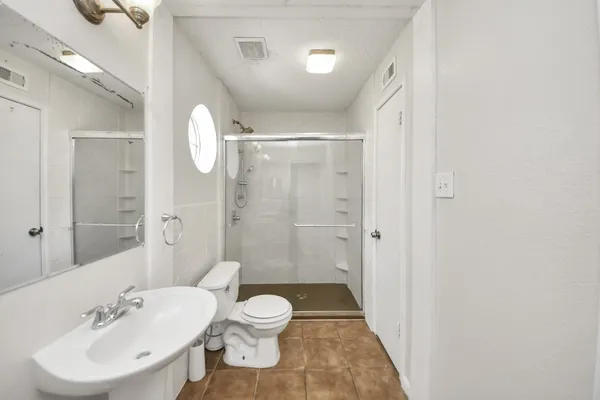a bathroom with a sink a toilet and shower