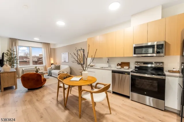 a kitchen with stainless steel appliances a stove a sink a microwave a dining table and chairs