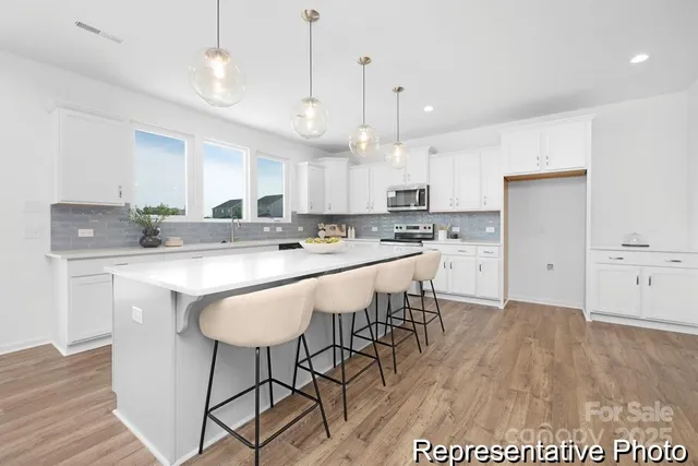 a kitchen with stainless steel appliances granite countertop a sink a stove a refrigerator and island with wooden floor