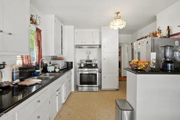 a kitchen with stainless steel appliances granite countertop a refrigerator a stove a sink dishwasher and a dining table with wooden floor