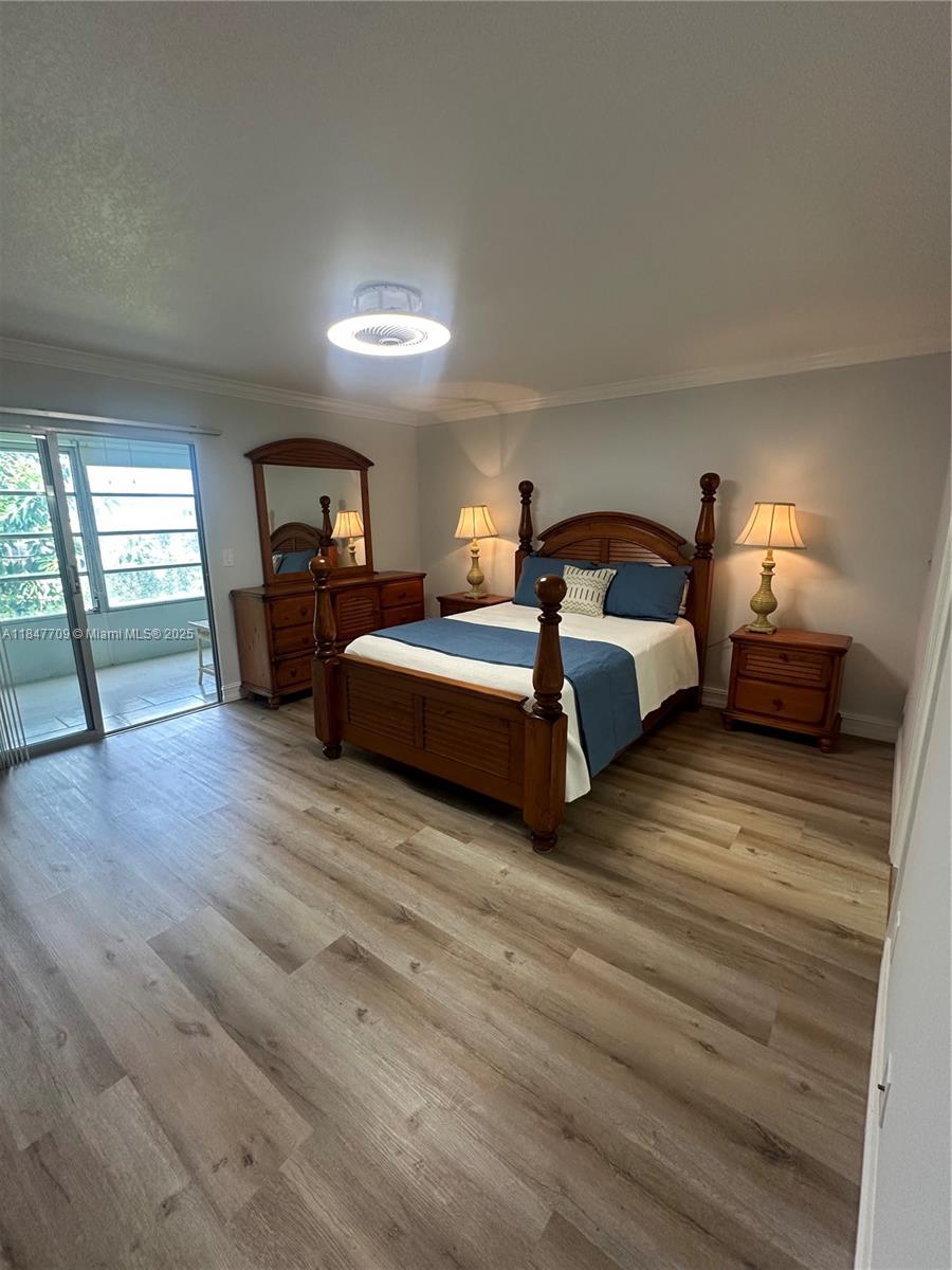 4027 Swansea Crescent, Unit 4027 Deerfield Beach, FL 33442 - Photo 26 of 47 a spacious bedroom with a bed and wooden floor