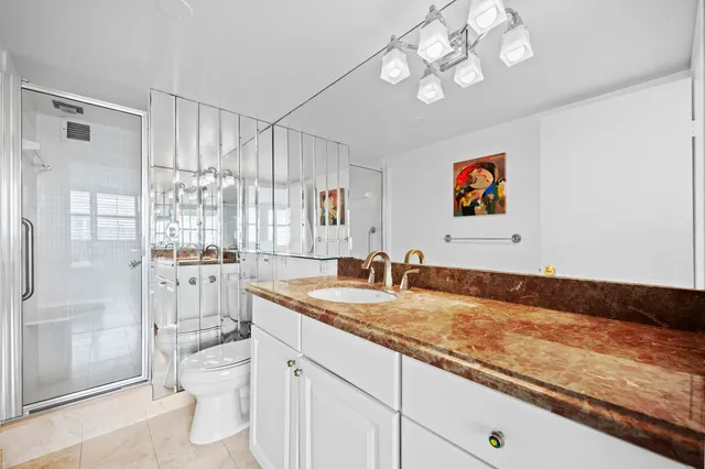 a bathroom with a granite countertop sink mirror vanity and toilet