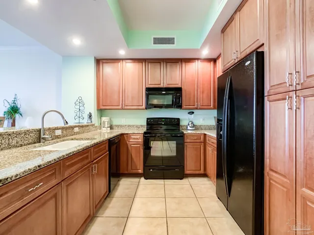a kitchen with granite countertop a refrigerator stove and sink