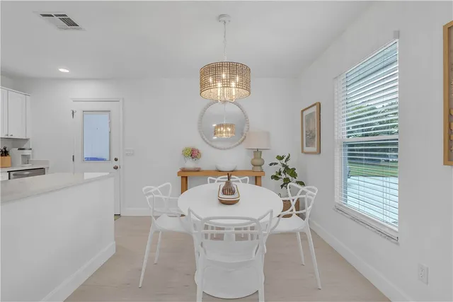 a kitchen with stainless steel appliances granite countertop a sink dishwasher a refrigerator and a dining table with wooden floor