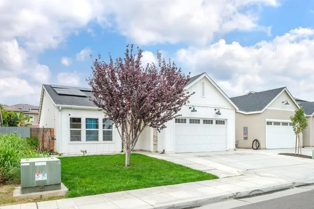 a front view of a house with a garden and trees
