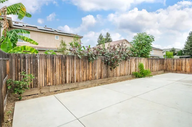 a backyard of a house with plants and wooden fence