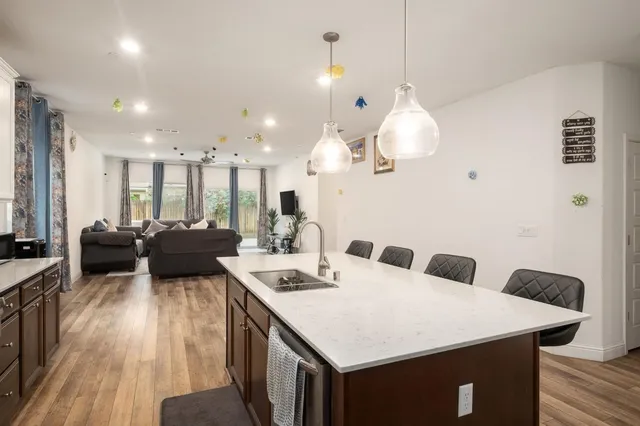 a large kitchen with a counter space a sink appliances and living room view