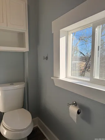 a white toilet sitting next to a window in a bathroom
