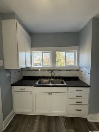 a kitchen with granite countertop a sink and a white cabinets
