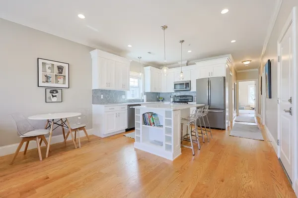 a kitchen with stainless steel appliances kitchen island granite countertop a table chairs refrigerator and microwave
