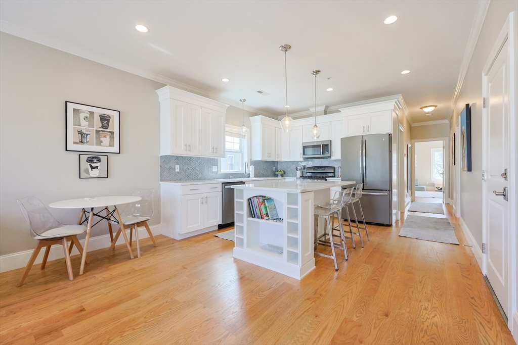17 Washington Avenue, Unit 3 Waltham, MA 02453 - Photo 4 of 38 a kitchen with stainless steel appliances kitchen island granite countertop a table chairs refrigerator and microwave